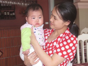 Liten vietnamesisk ansatte med sin 4 måneder gammel baby.